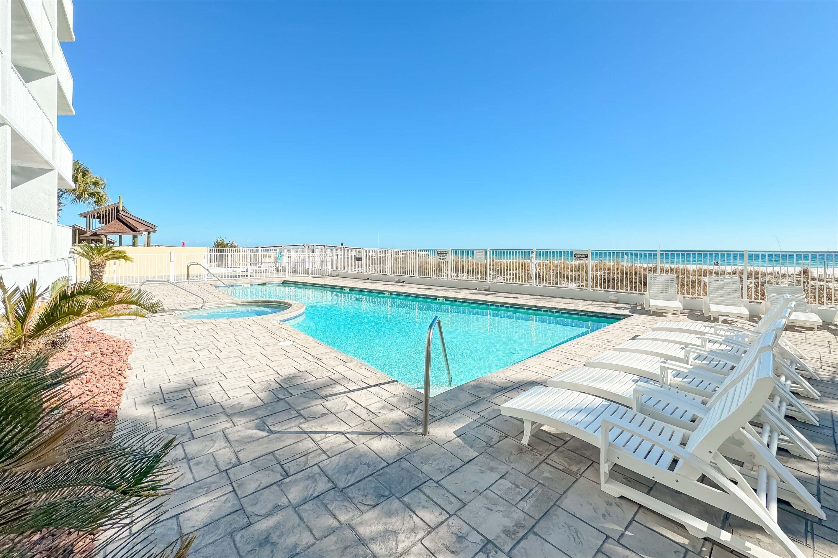 Un espace piscine avec des chaises longues et vue sur l’océan.