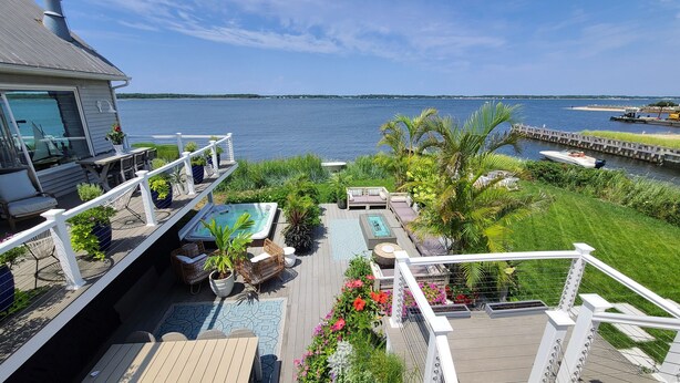 A deck with a hot tub, outdoor furniture, and a view of the water.