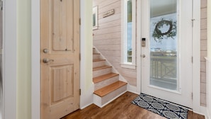 A wooden staircase leading to a door with a glass panel and a wreath.