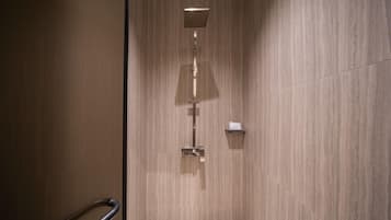 A modern shower with a square head and a vertical handle, set in a room with wooden paneling.