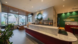 A modern hotel lobby with a marble reception desk, a green wall with the hotel name, and a large window offering a view of the city. - Daegu Eastern Hotel Lions Park (Daegu)
