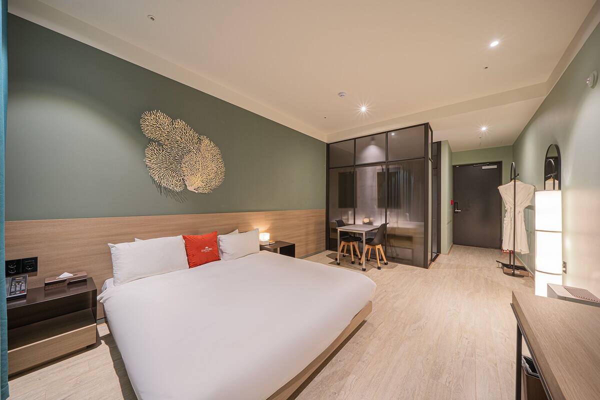 A hotel room with a large bed, a desk, and a mirror.