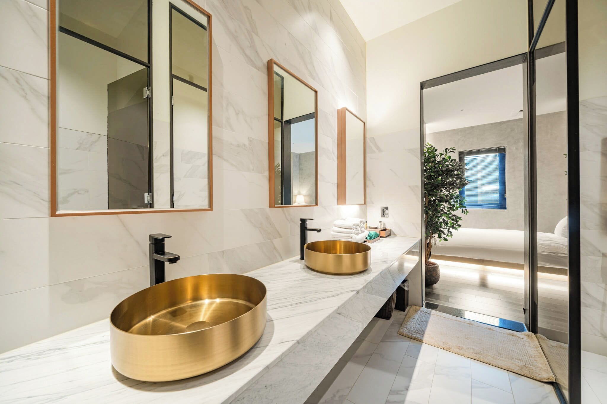 A modern bathroom with two sinks, large mirrors, and a large window.