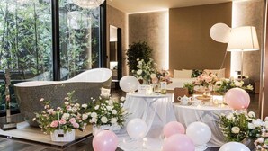 A room with a large bathtub, floral arrangements, balloons, and a table with a sign. - Daegu Eastern Hotel Lions Park (Daegu)