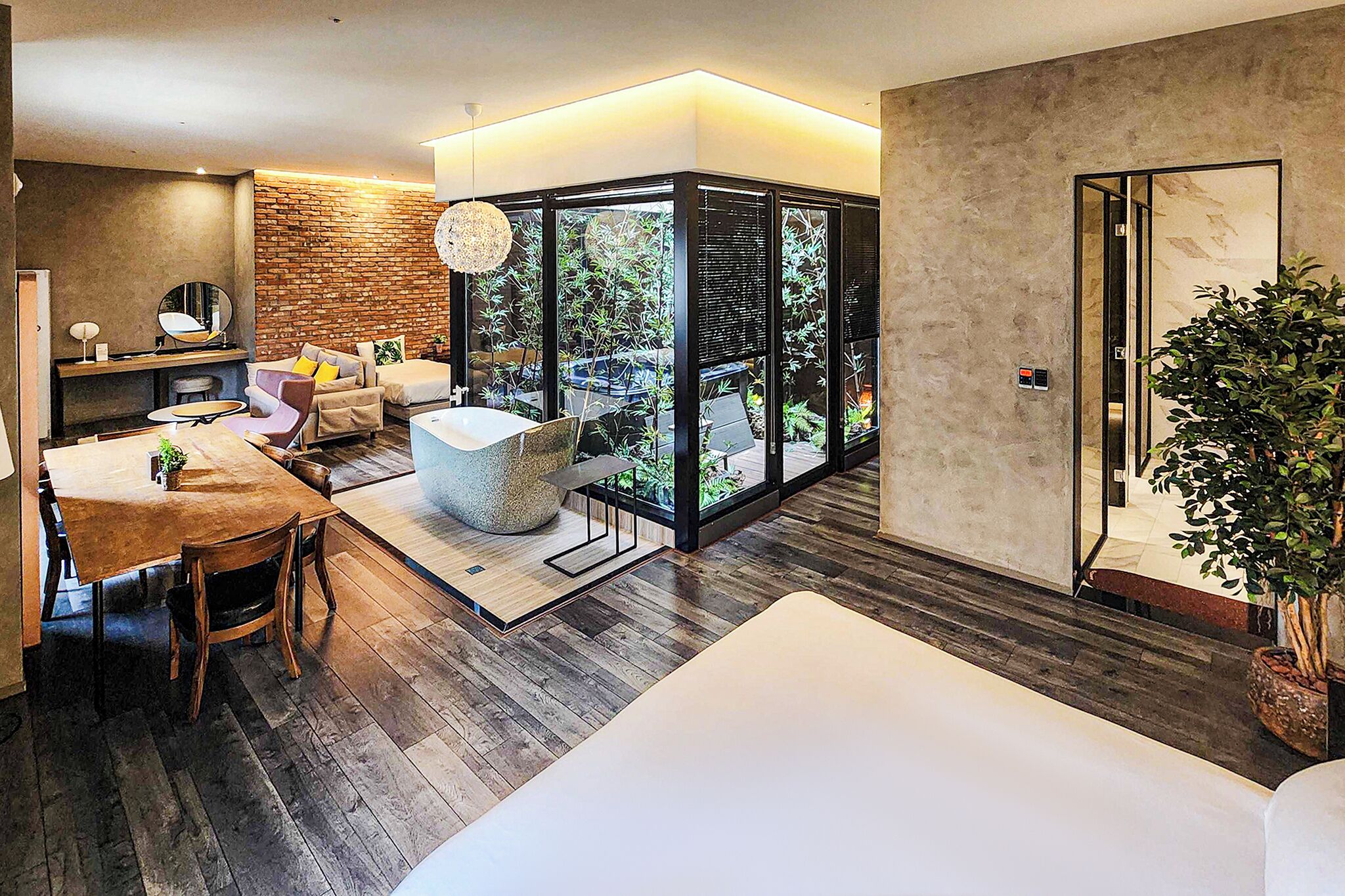 A modern interior with a dining area, seating, a large window, and a plant.