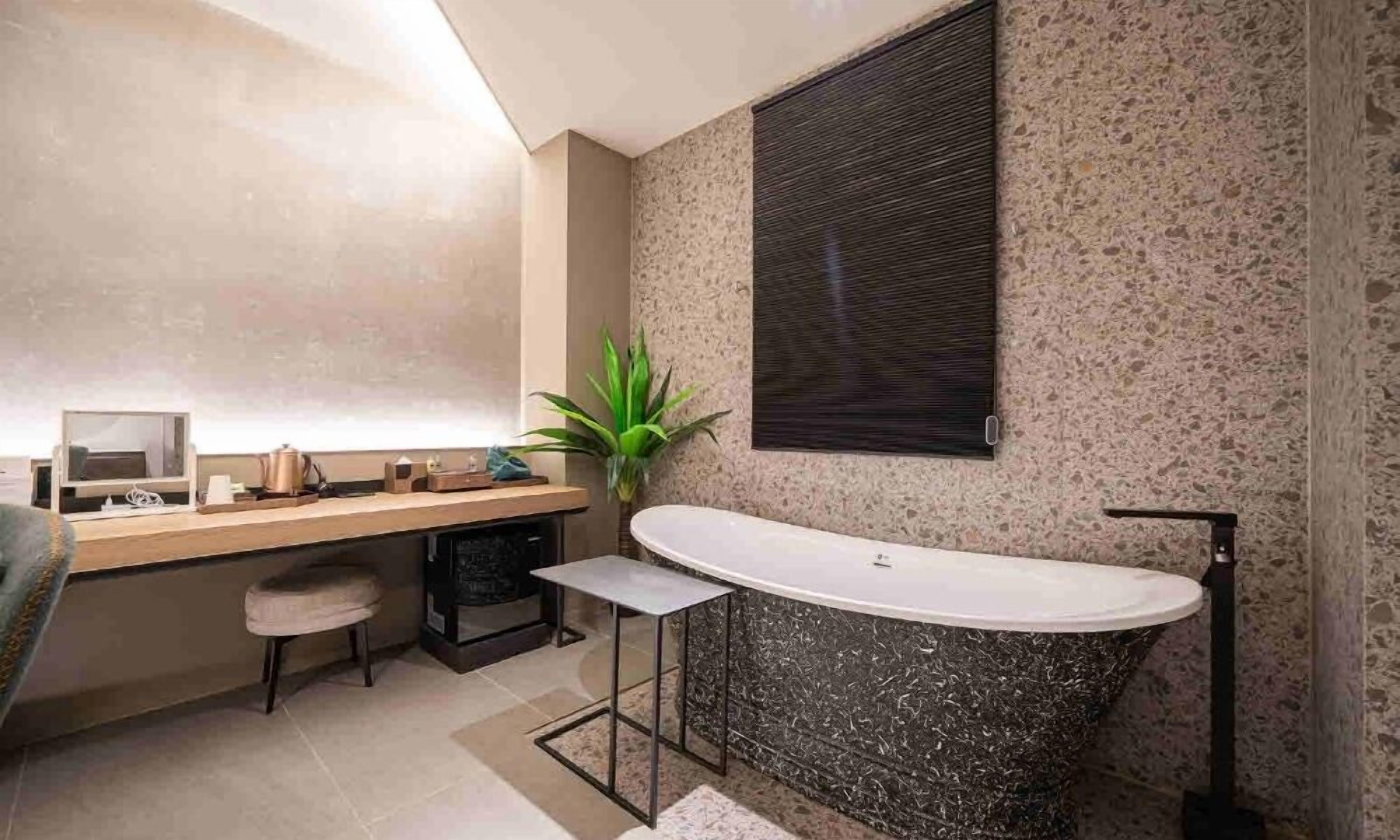 Un baño moderno con una bañera independiente, un tocador con espejo y una planta en maceta.