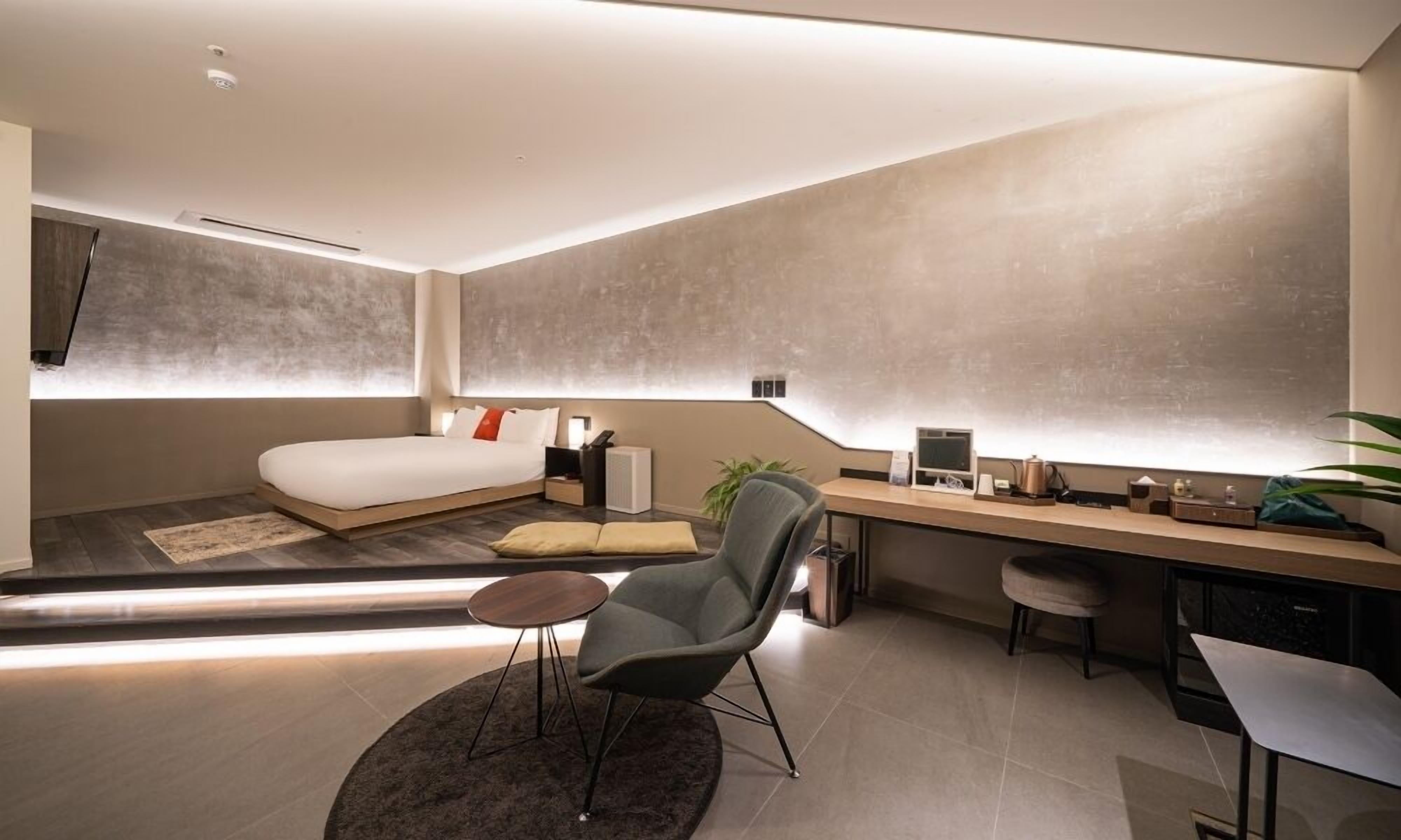 A modern bedroom with a large bed, a desk, and a chair.