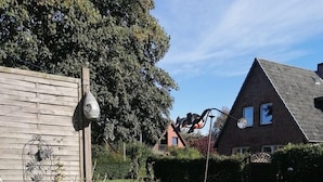 En have med plantekrukker, fugle foderautomat og skulptur.