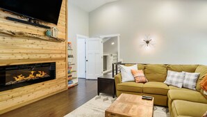 Una sala de estar con chimenea, televisor, sofá y mesa de centro.