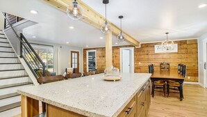 Una cocina amplia con una isla grande, detalles de madera e iluminación colgante.