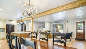 Una cocina amplia con una isla de madera, un área de comedor con mesa y sillas de madera, y una escalera que lleva a un balcón.