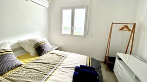 A bedroom with a bed, a wooden hanger, a white dresser, and a window. - Villa Saphir Equipée (Gourbeyre)