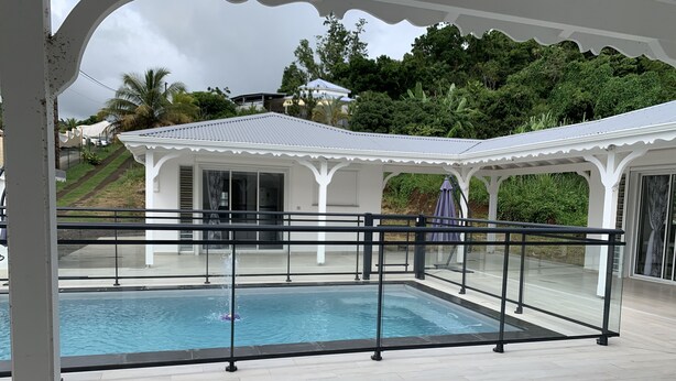 A swimming pool with a white gazebo and a view of a house and trees in the background. - Villa Saphir Equipée (Gourbeyre)