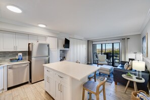 Een moderne keuken met witte kasten, een centraal eiland en een zithoek met een bank en tafel.
