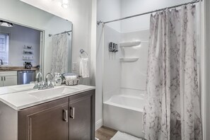 Een bad/douchecombinatie, een haardroger, handdoeken, zeep