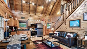 A cozy log cabin interior with a dining area, kitchen, and living room. - Buddy’s Mountain Hideaway (Sevierville)
