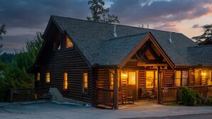 A log cabin with a porch, multiple windows, and a chimney. - Heated Rst Pool-Dollywood-WIFI -Arcade-Parkway-Families-Shopping-Hot Tub-Shows (Pigeon Forge)