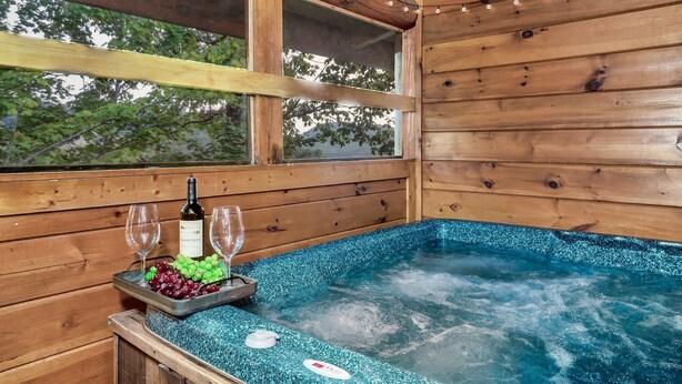A wooden cabin with a hot tub, a bottle of wine, and a tray of grapes. - Heated Rst Pool-Dollywood-WIFI -Arcade-Parkway-Families-Shopping-Hot Tub-Shows (Pigeon Forge)