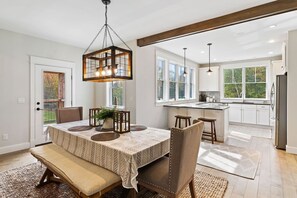 Enjoy dining and socializing in this inviting space with a large table for four, comfortable seating, and a modern pendant light.