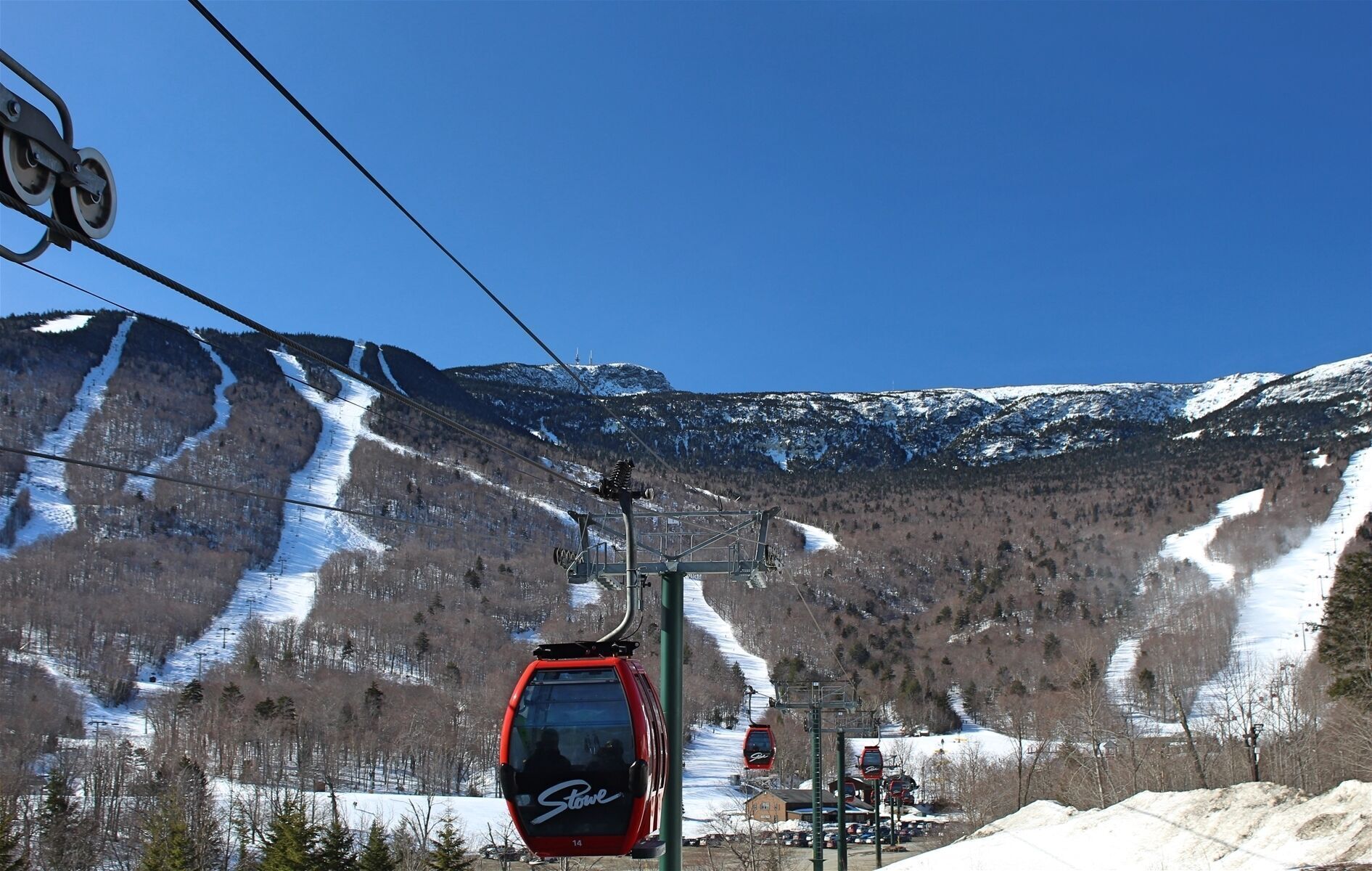 A cable car system with a mountainous backdrop, ski slopes, and a clear sky.