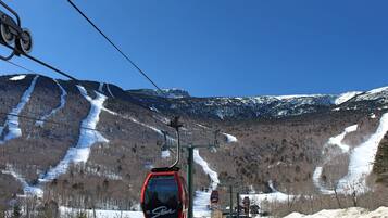 A cable car system with a mountainous backdrop, ski slopes, and a clear sky.