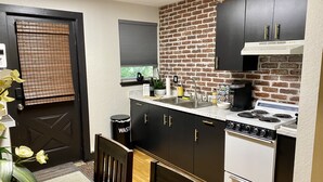 A compact kitchen with dark cabinets, a white stove, and a window with blinds.