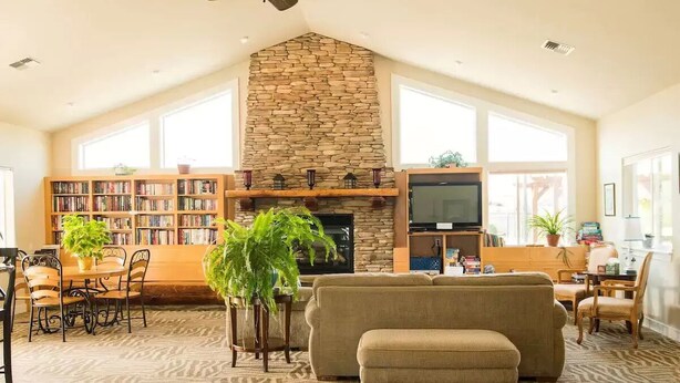 Un salón amplio con chimenea de piedra, una estantería grande, un sofá cómodo y un televisor.