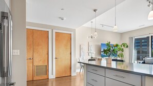 Una cocina moderna con una isla grande, puertas de madera y vistas de la ciudad a través de amplios ventanales.