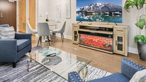 Una sala de estar moderna con chimenea, zona de estar y un televisor grande montado en la pared.