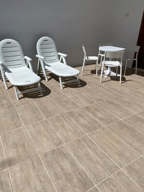 A patio with two lounge chairs and a small table.