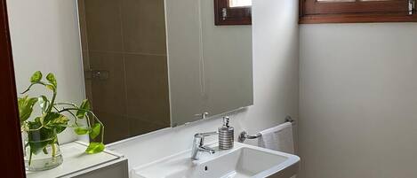 A bathroom with a white sink, a mirror, and a window with wooden frames.