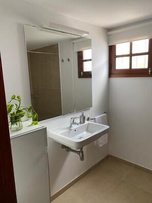 A bathroom with a white sink, a mirror, and a window with wooden frames.