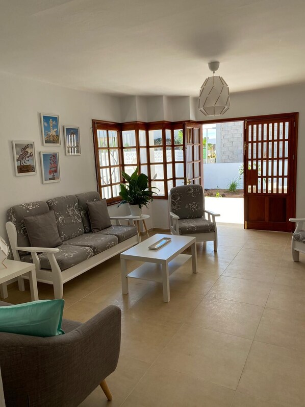 A living room with a sofa, armchairs, a coffee table, and a potted plant.