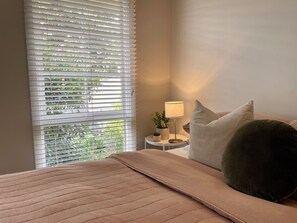 Relax in this serene bedroom with a comfortable bed, bedside table, and a potted plant.