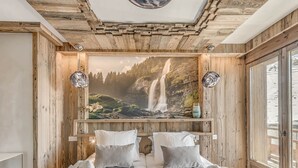 A bedroom with a large bed, two side tables, a mural of a waterfall, and wooden walls. - 5* Chalet in Tignes - 450m² - 16 guests - Sauna, Jacuzzi, Game Room (Tignes)