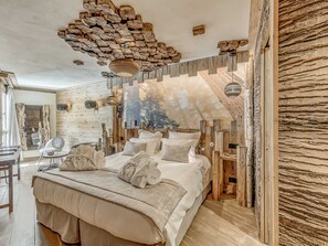 Une chambre dotée d’un grand lit, d’une tête de lit en bois et d’un décor de plafond original.