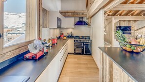 A modern kitchen with wooden accents, a large window, and a view of a snowy landscape. - 5* Chalet in Tignes - 450m² - 16 guests - Sauna, Jacuzzi, Game Room (Tignes)
