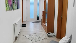Een gang met een houten plafond, een bank en een deur met een spiegel.