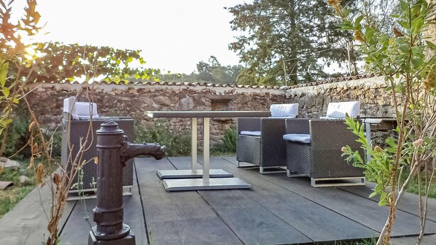 An outdoor patio with a stone wall, a metal fire hydrant, and wicker furniture. - Cozy home in La Souterraine (La Souterraine)