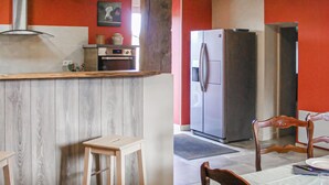 A kitchen with a wooden countertop, a built-in oven, a refrigerator, and a dining area with a table and chairs. - Cozy home in La Souterraine (La Souterraine)