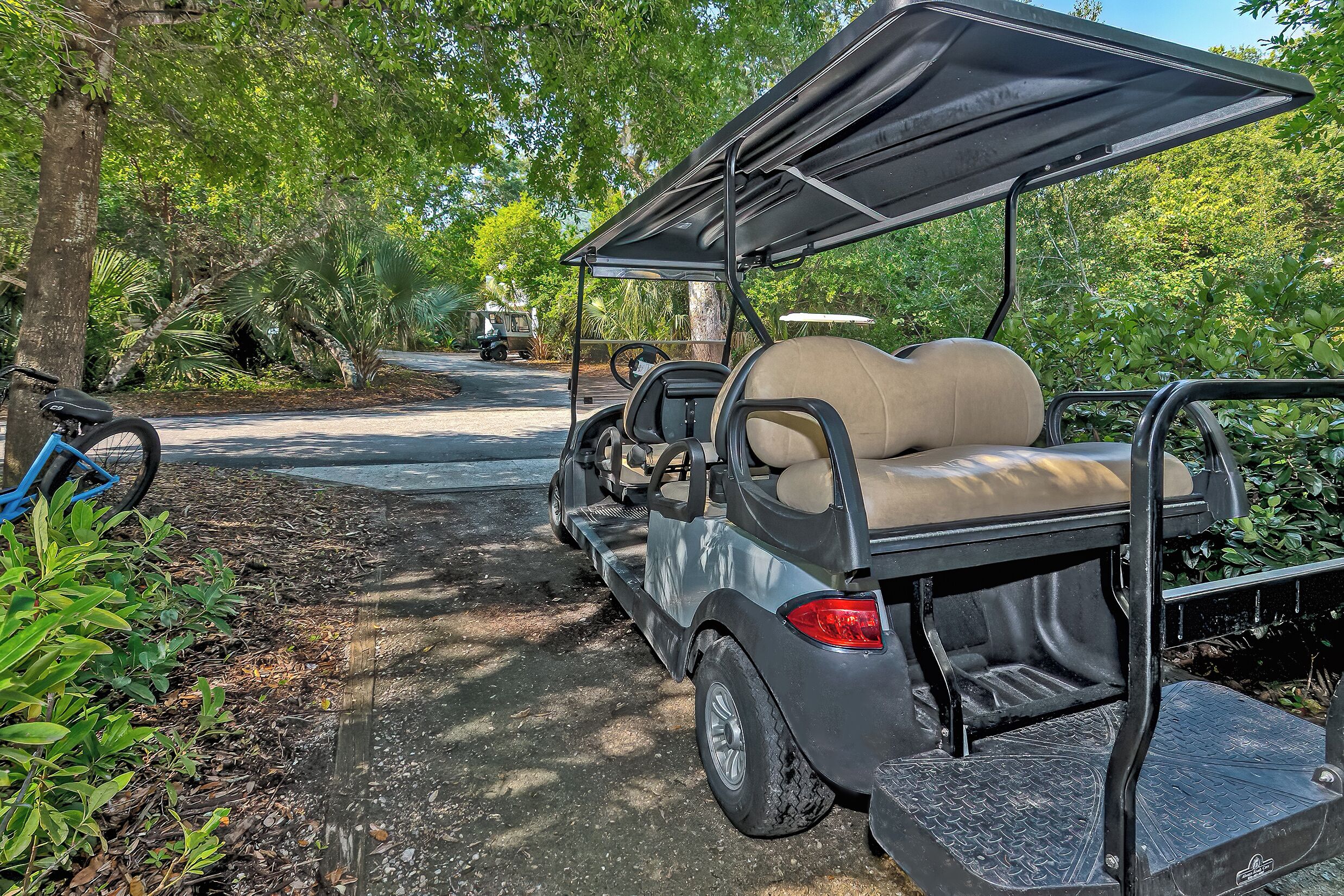 Een golftrolley geparkeerd in een bebost gebied met een verhard pad.