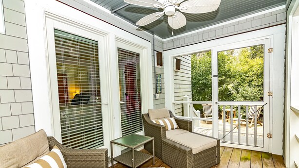 A covered porch with wicker furniture, a ceiling fan, and a view of the backyard. - Reverse floor plan cottage with screened in porch. Nature views! (Bald Head Island)
