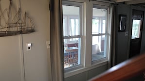 A room with a large window, a door, and a wall-mounted light switch.