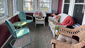 A cozy room with a wicker sofa, a wicker chair, and a small table with a lamp and flowers.