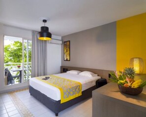 Relax in a spacious room with a large bed, balcony, and views of lush greenery.