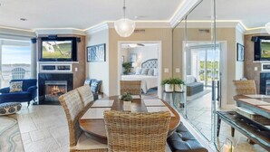 A spacious living room with a fireplace, a dining area with wicker furniture, and a bedroom visible through a glass door. - GWEN'S GETAWAY!!, TOP FLOOR! 10 Mile View, Kid Friendly! (Osage Beach)