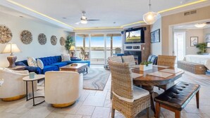 A spacious living area with a blue sofa, wicker chairs, a wooden dining table, and a ceiling fan. - GWEN'S GETAWAY!!, TOP FLOOR! 10 Mile View, Kid Friendly! (Osage Beach)