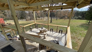 Une terrasse en bois avec une table et des chaises, entourée d’une clôture en fil de fer.