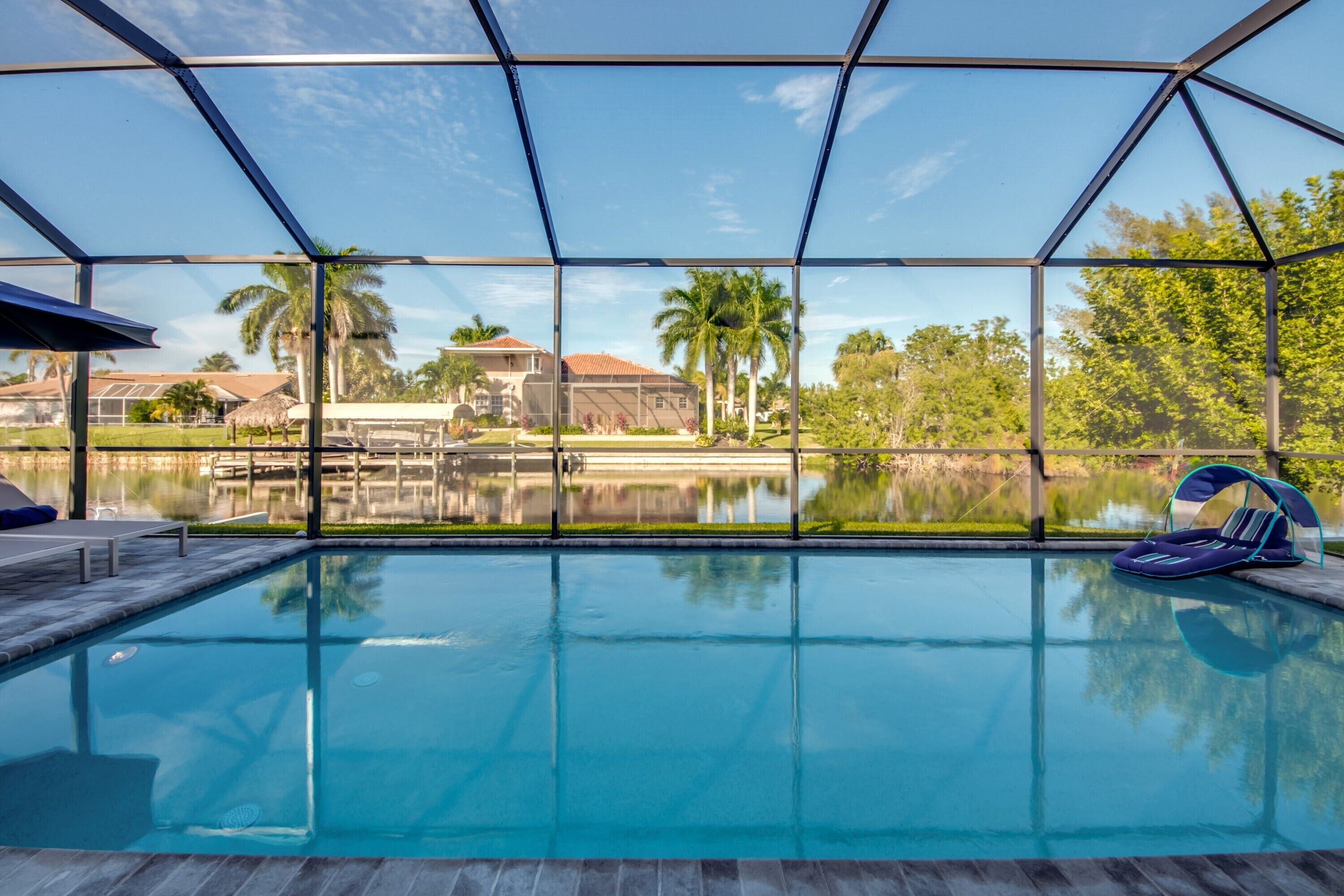 Une piscine offrant une vue dégagée sur les environs, notamment sur une maison et des palmiers.