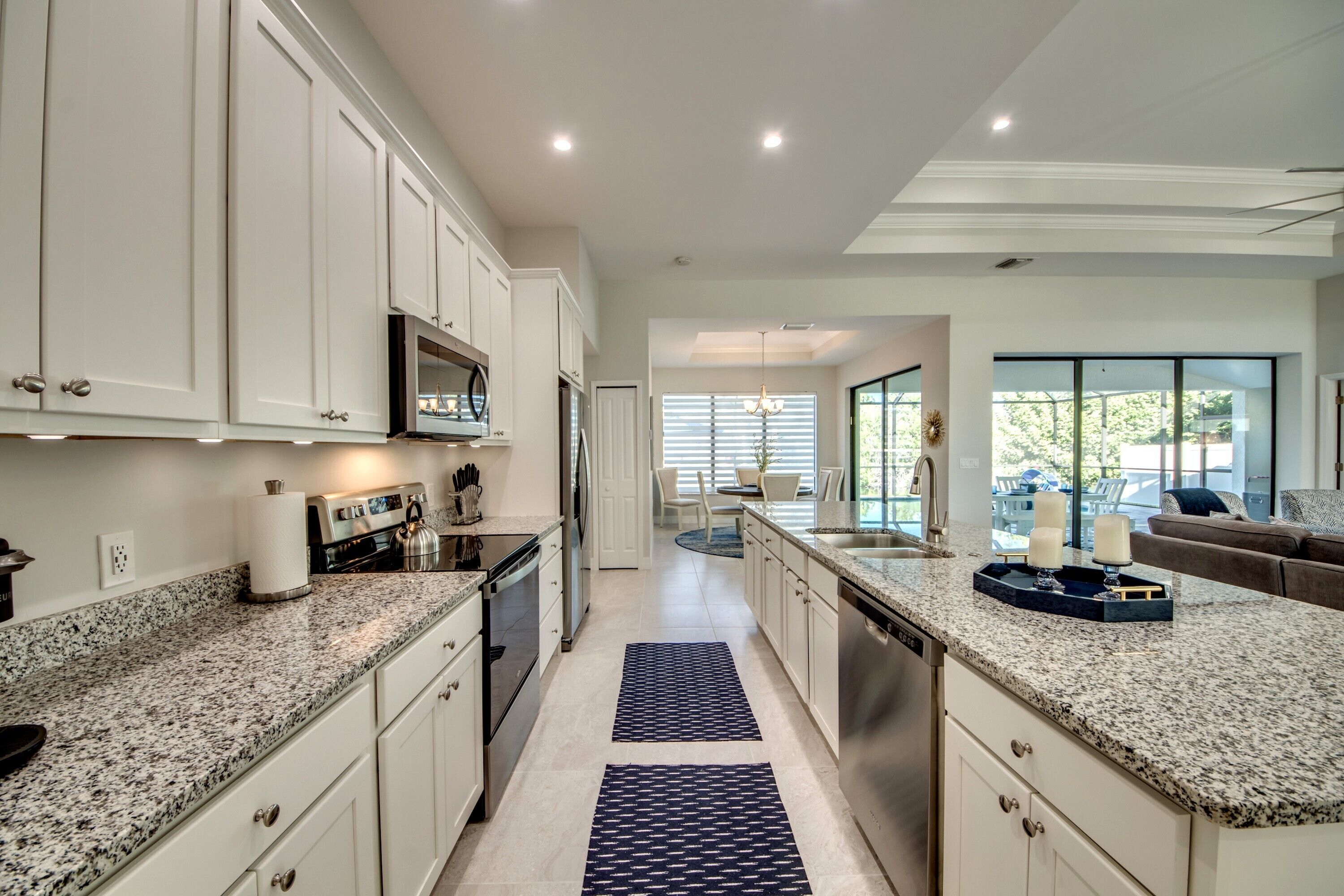 A modern kitchen with white cabinets, granite countertops, and stainless steel appliances.